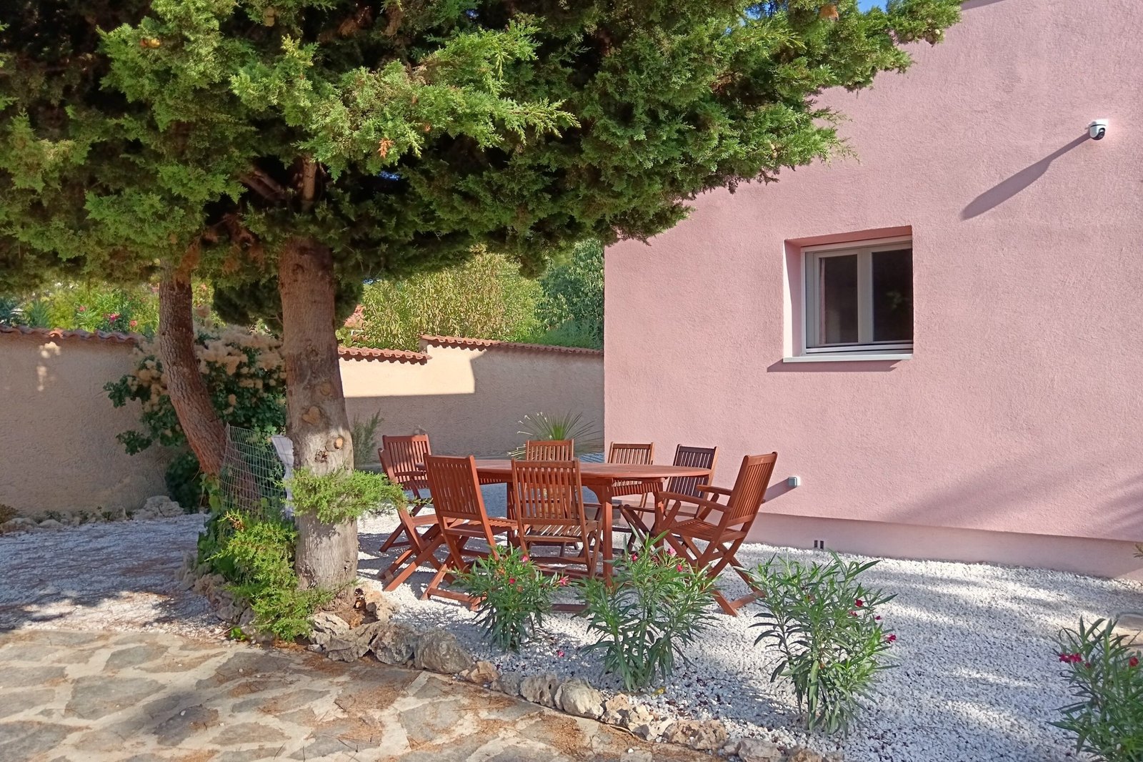 La grande table extérieure et ses huit chaises sous la pergola